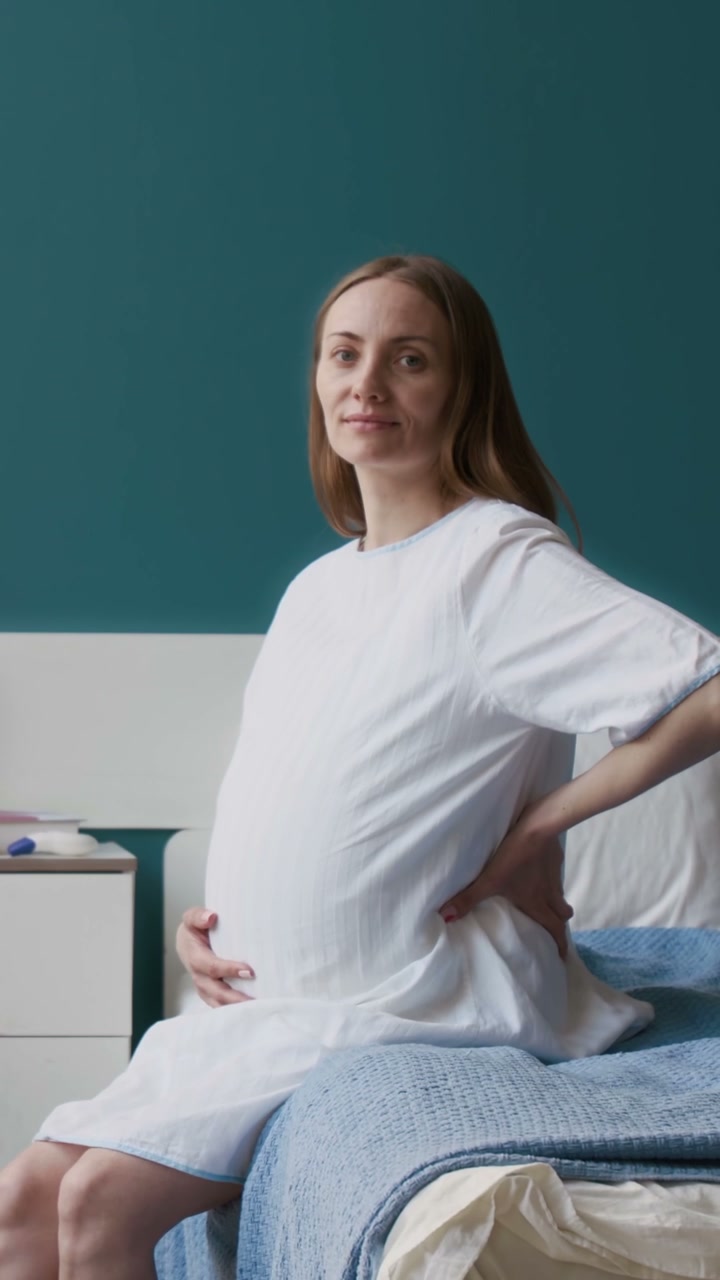 Pregnant Woman Touching Belly and Smiling on Bed
