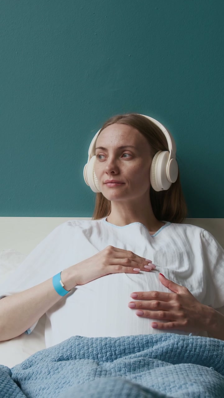 Pregnant Woman Listening to Music in Hospital Bed