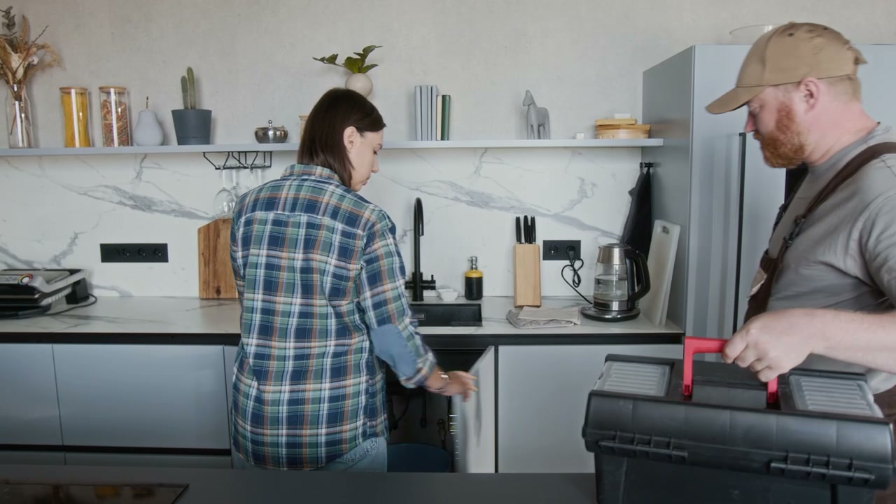 Plumber and Homeowner Fixing Kitchen Sink