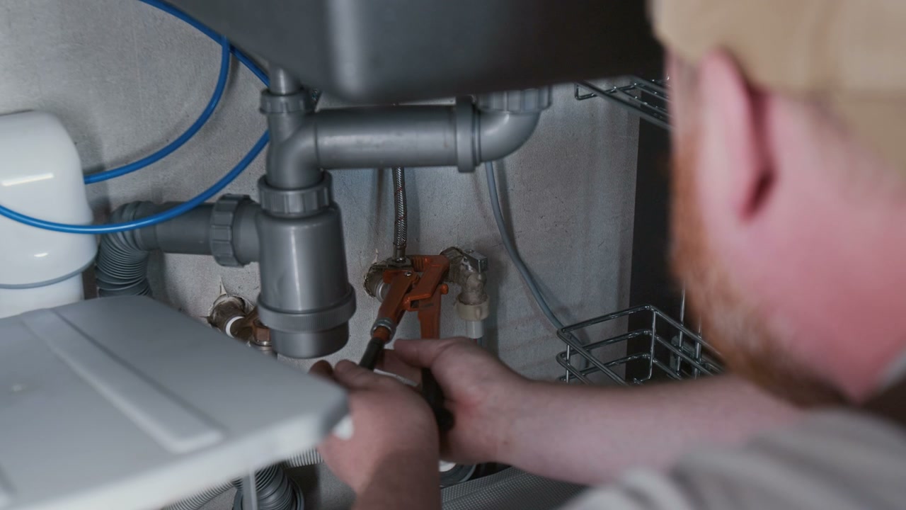 Plumber Fixing Sink using Pipe Wrench