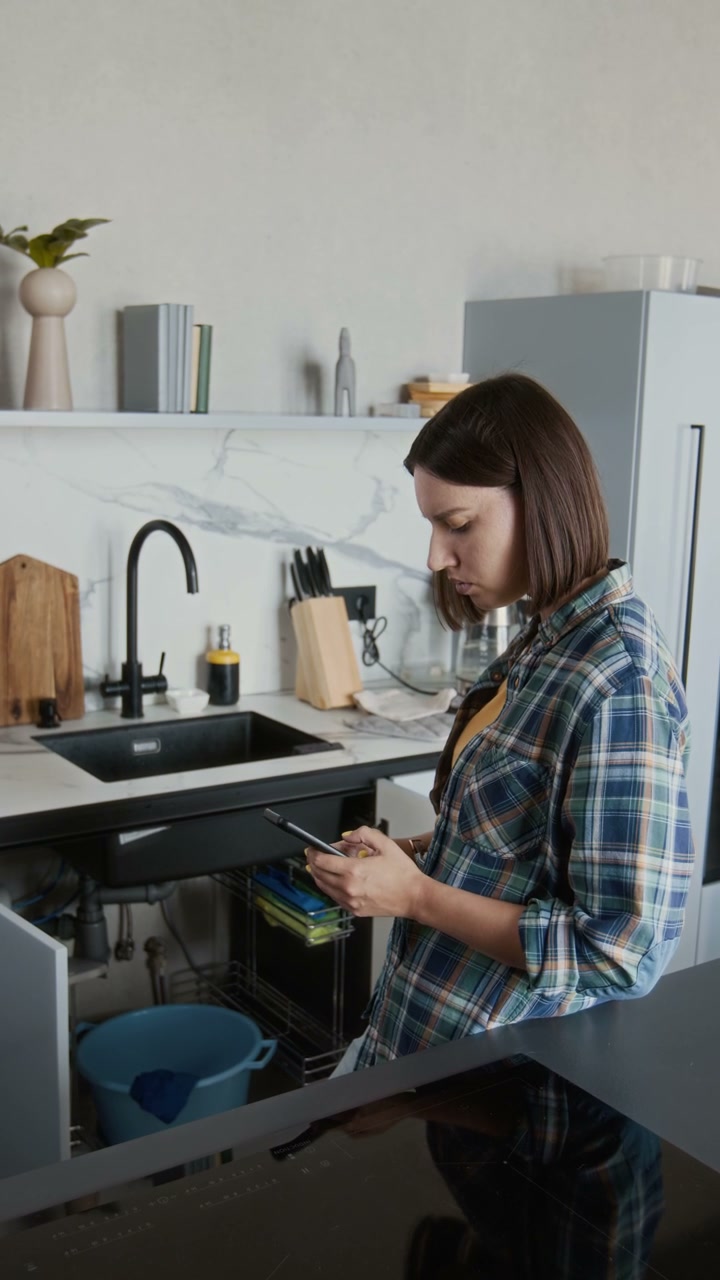 Woman Using Phone for Leaky Sink Repair
