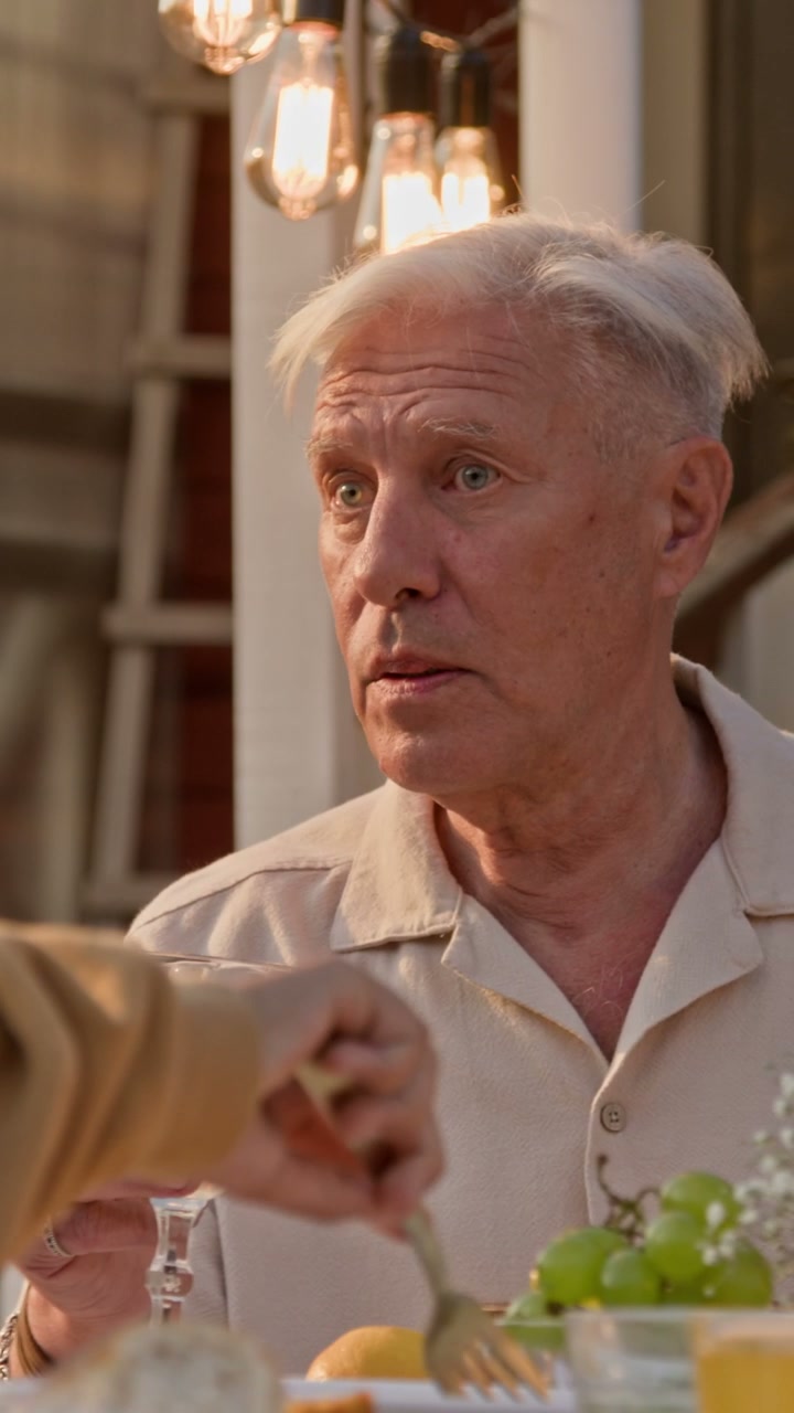 Senior Man Conversing at Outdoor Dining Table