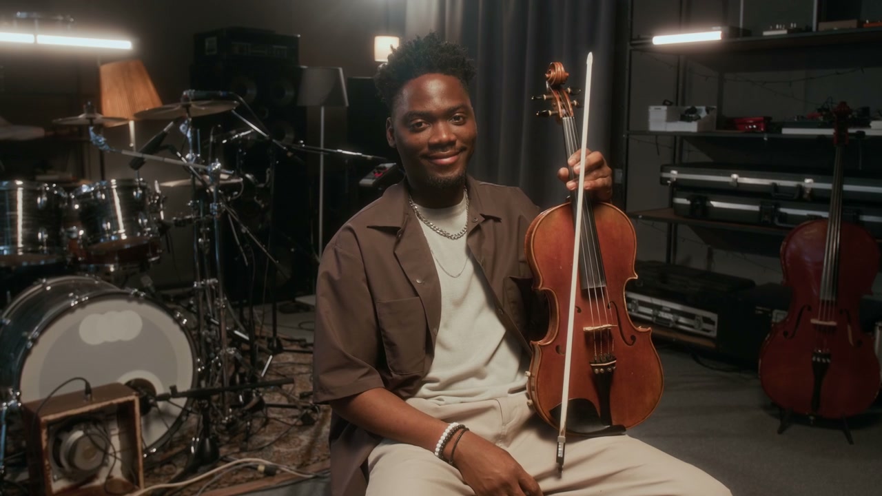 Smiling Man Holding Violin in Music Studio