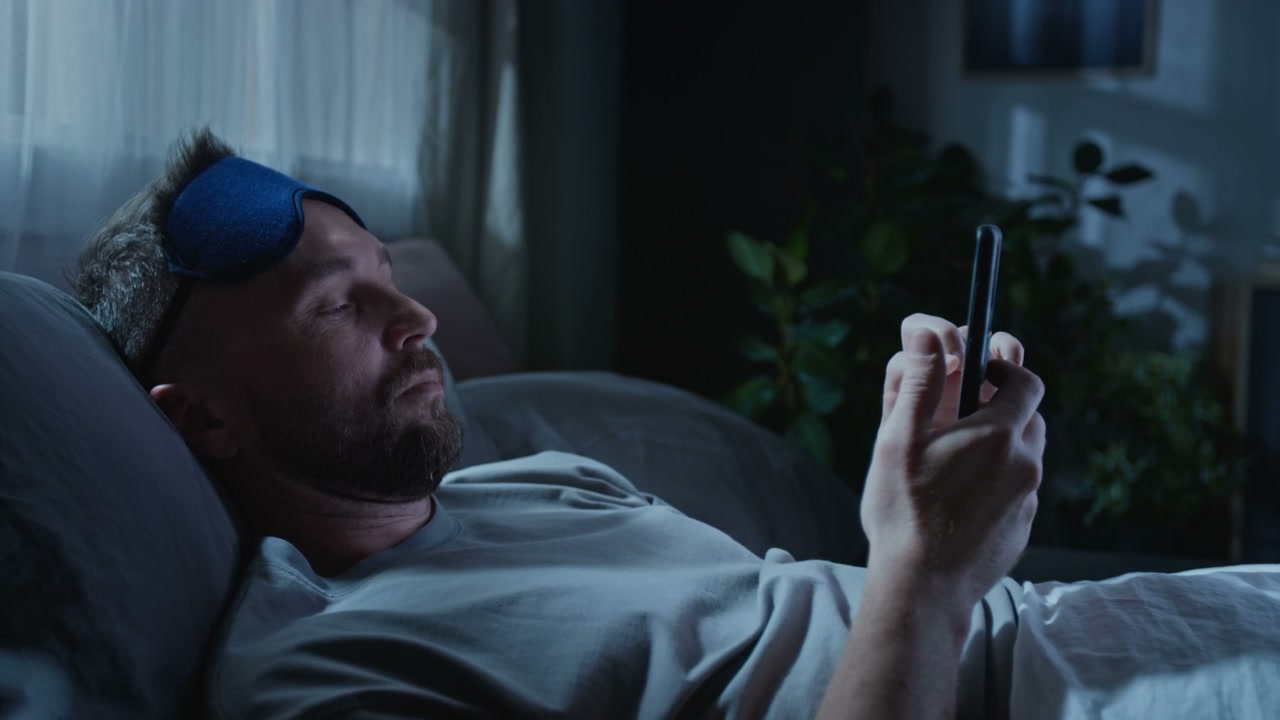 Man Using Smartphone in Bed at Night