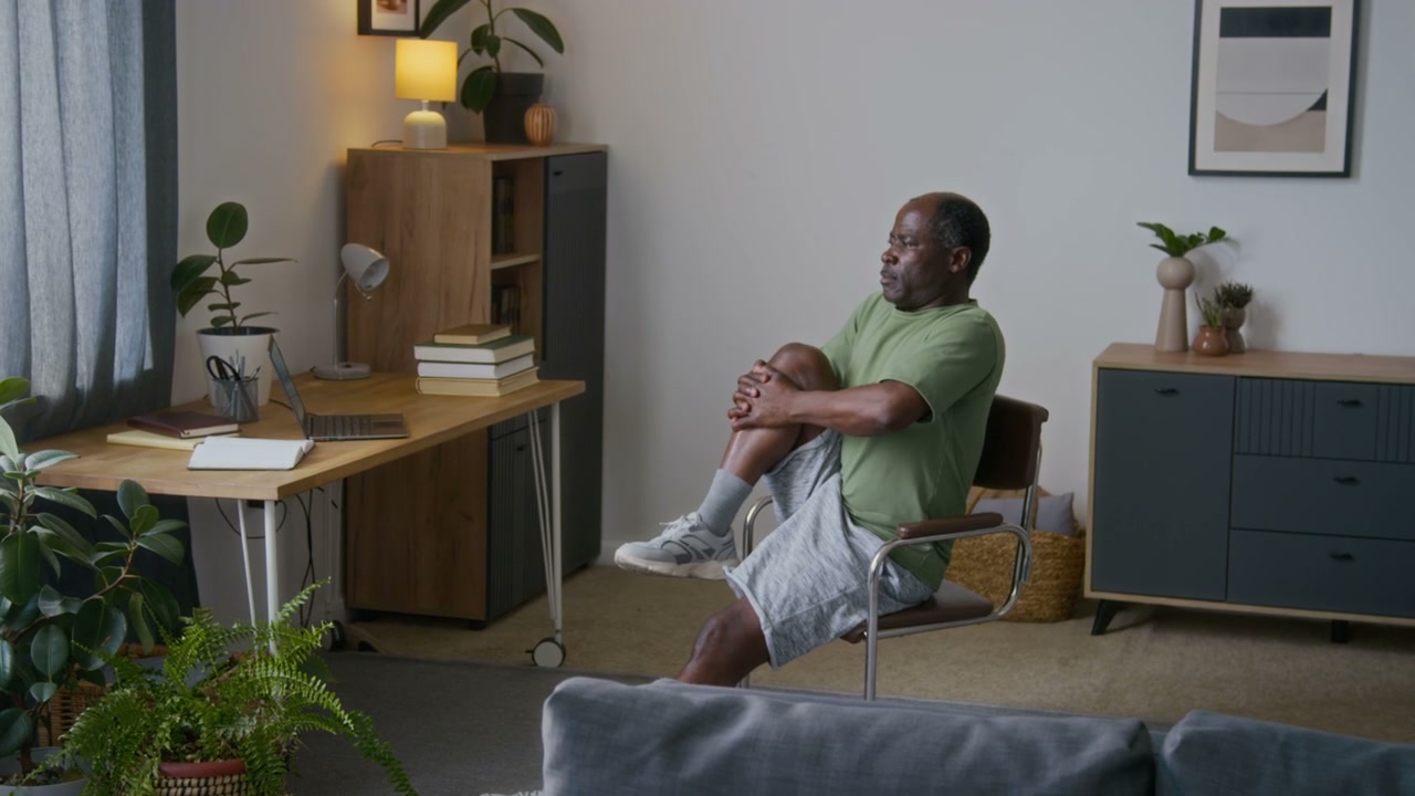 Senior Man Stretching in Home Office Chair