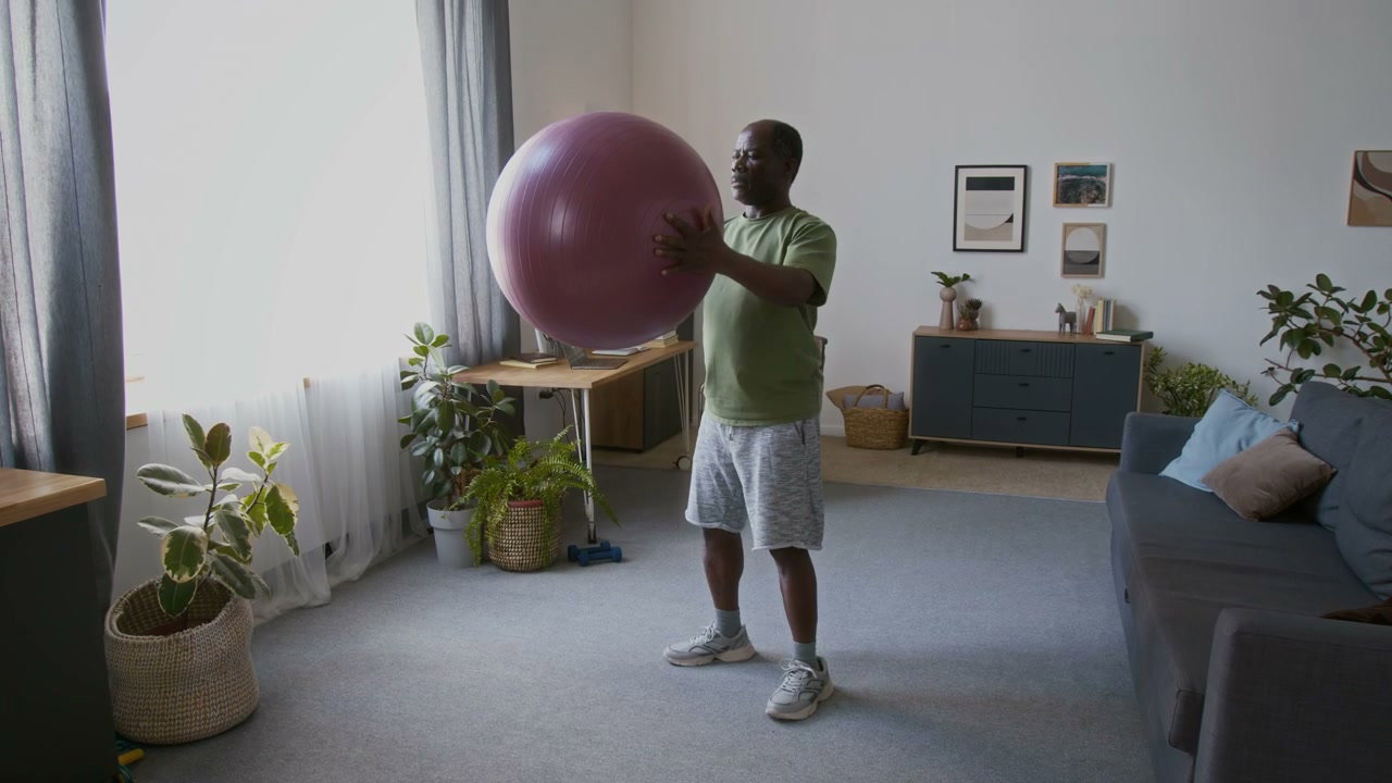 Senior Man Squatting with Fitness Ball at Home