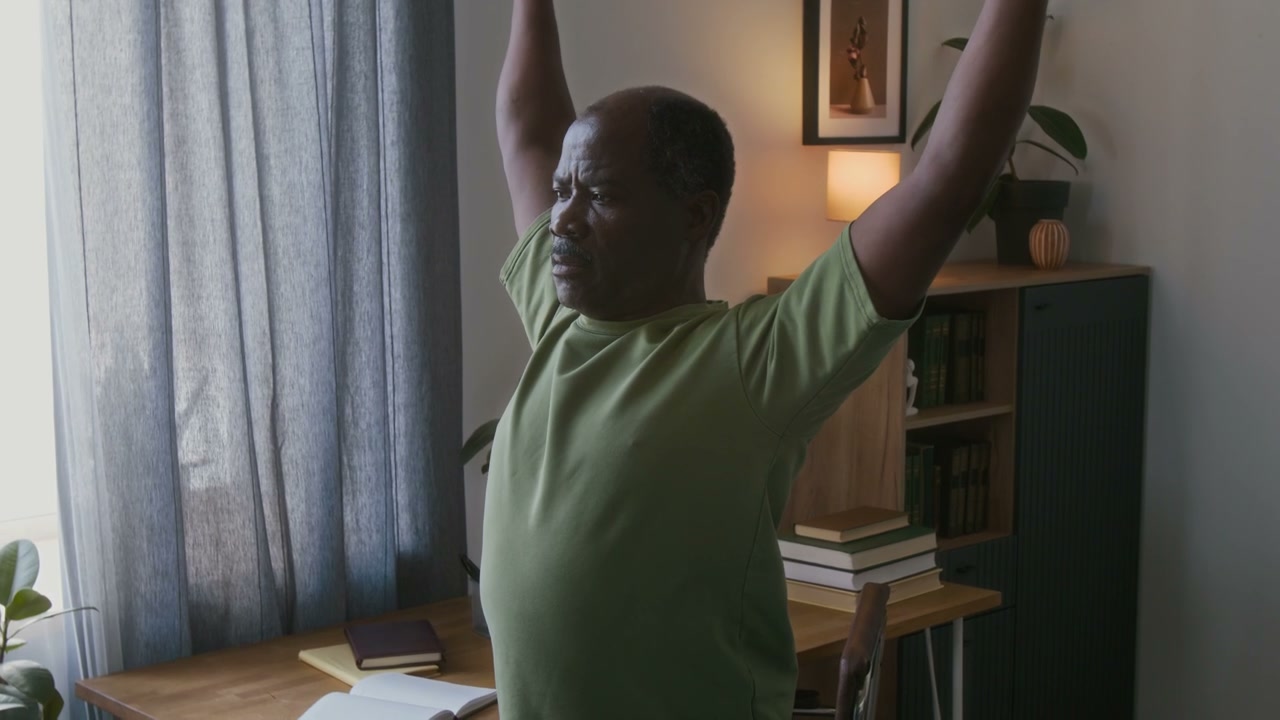 Senior Man Stretching Arms with Towel at Home