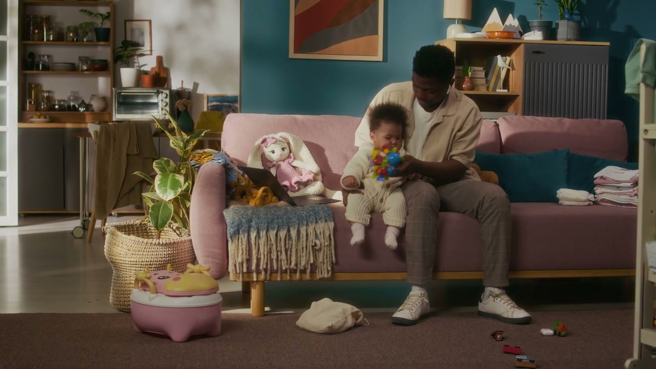 Black Father Playing With Baby On Sofa