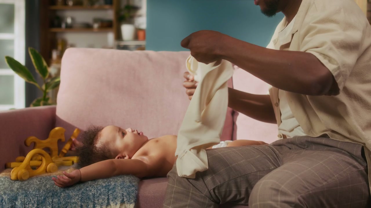 Father Dressing Baby on Sofa