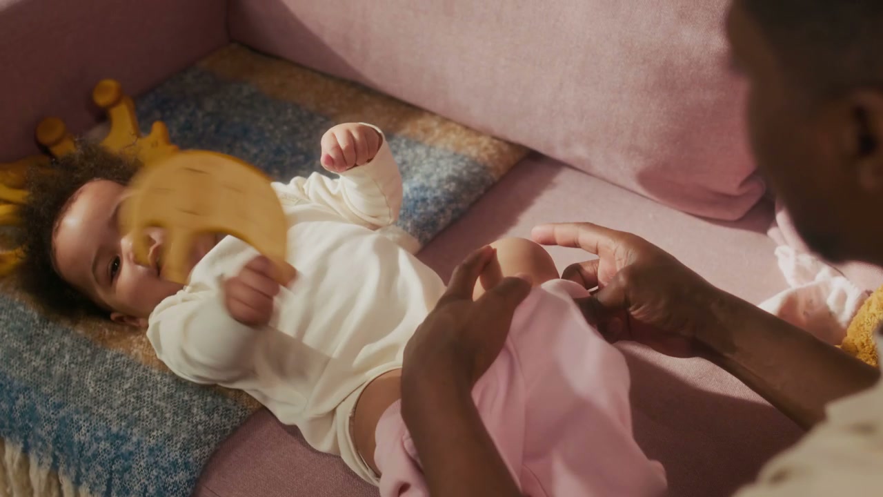 Dad Dressing Baby Girl on Sofa