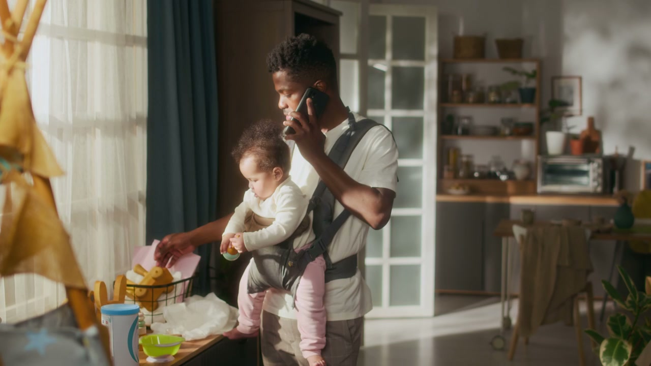 Father Multitasking with Baby in Carrier at Home