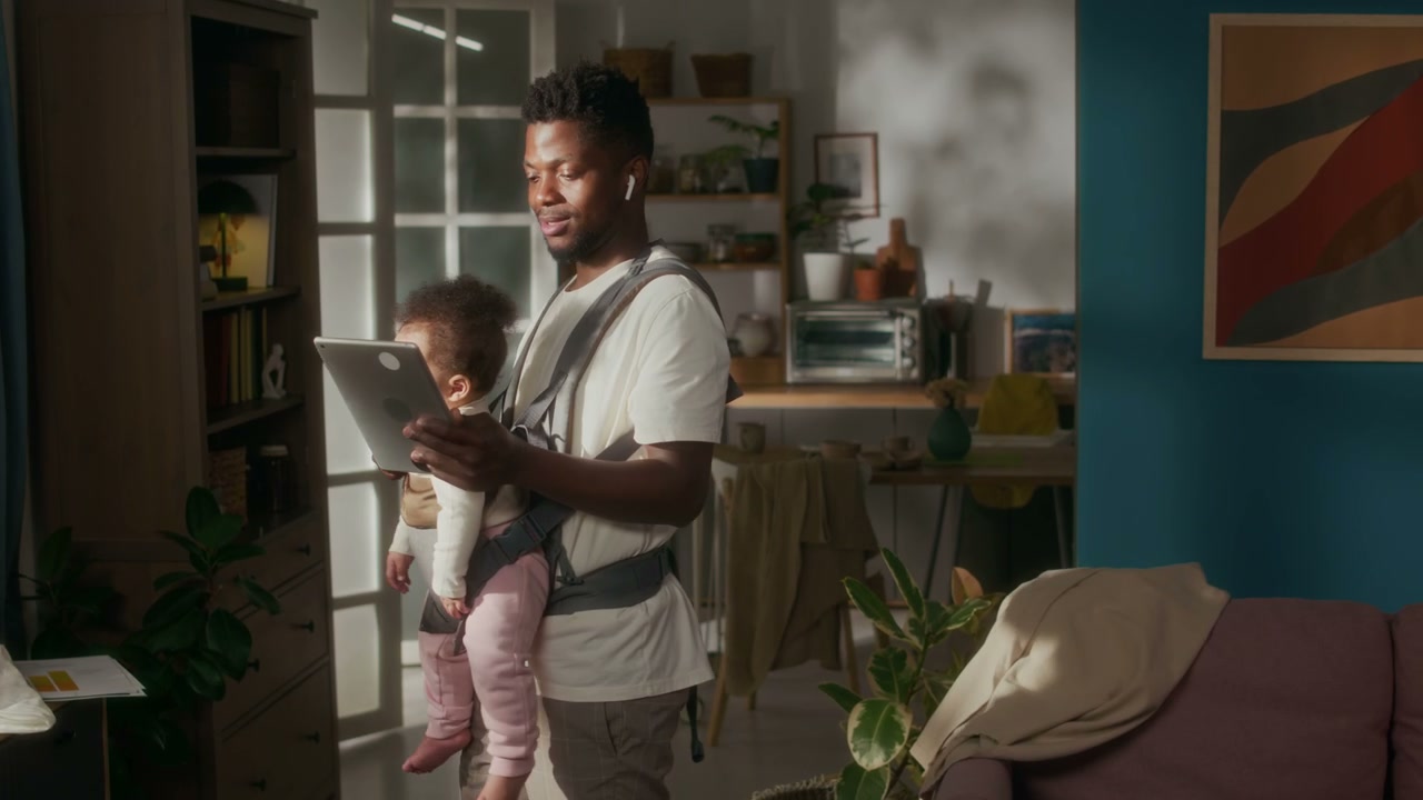 Father Working with Baby in Carrier at Home
