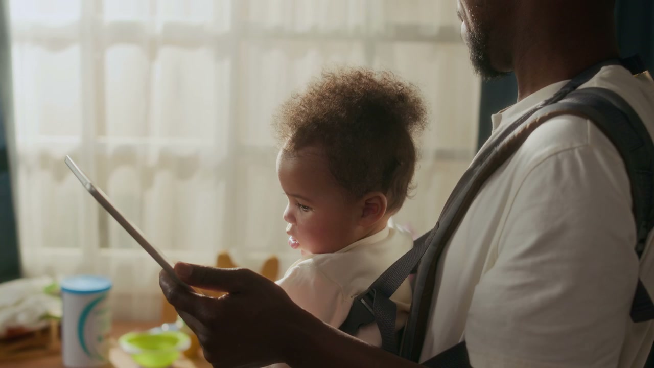 Father Multitasking with Baby and Tablet