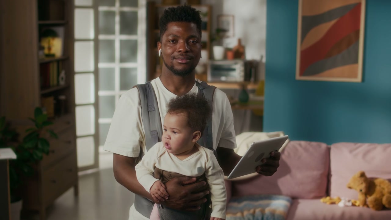 Father Holding Baby in Carrier with Tablet