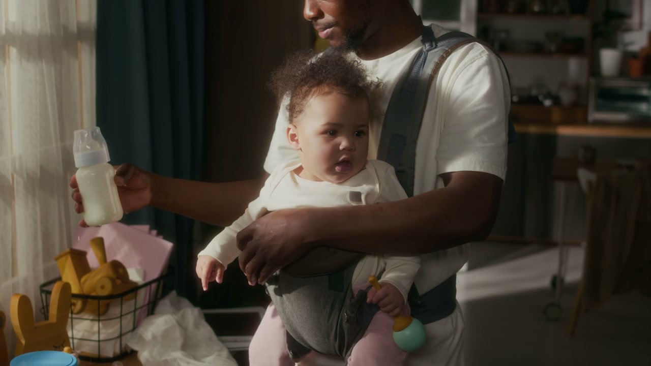 Father Cradling Baby in Carrier at Home
