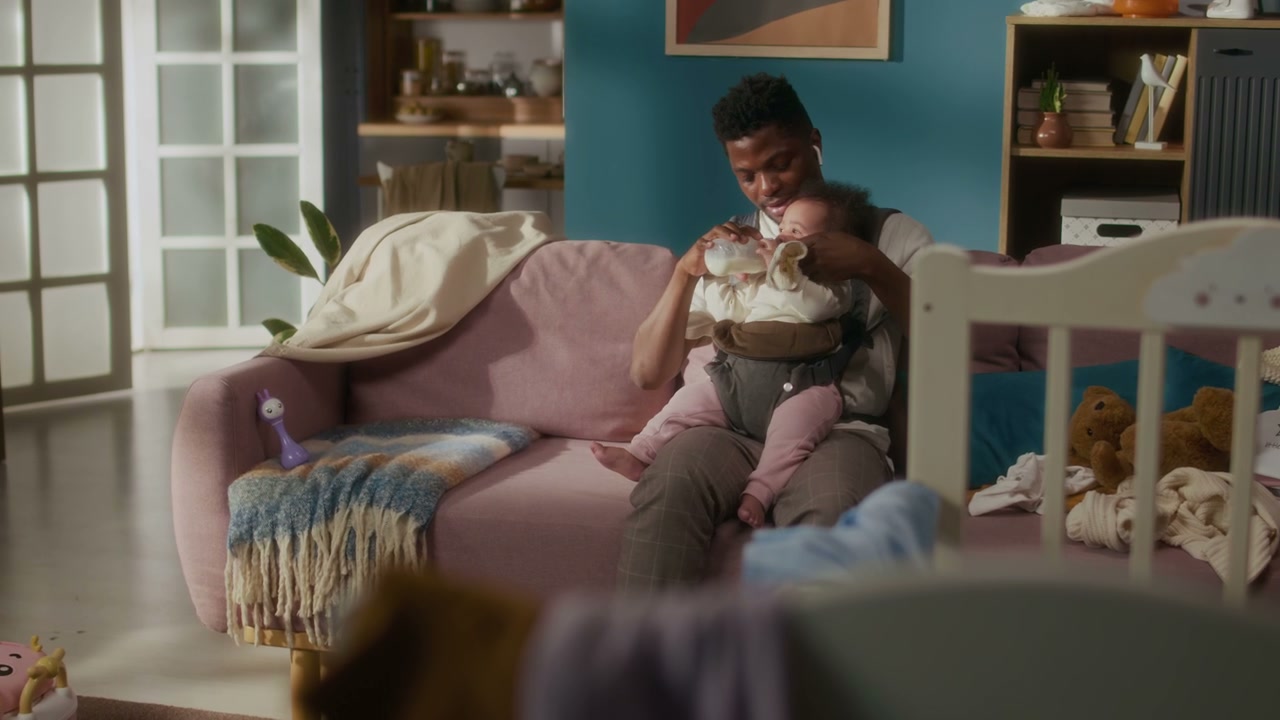 Father Bottle-Feeding Baby Girl on Sofa