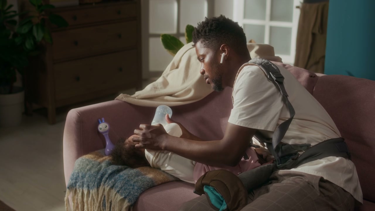 Father Bottle-Feeding Infant Daughter on Sofa