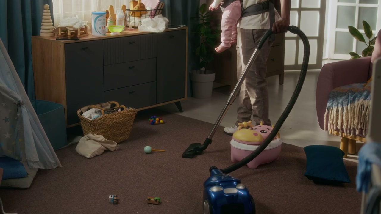 Father Vacuuming Home While Carrying Baby