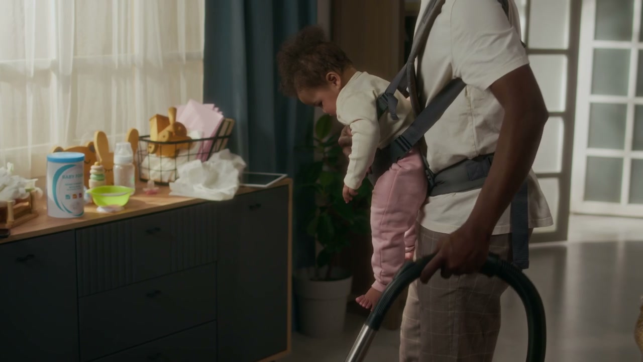 Black Father Vacuums Home While Babywearing Daughter