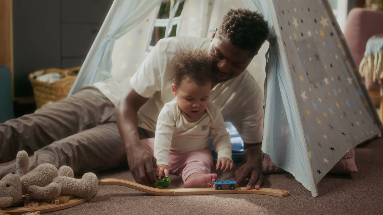 Father and Baby Playing with Toy Train in Tent