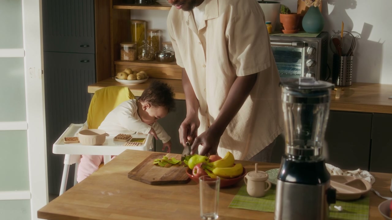 Dad Peeling Fruit for Baby in High Chair