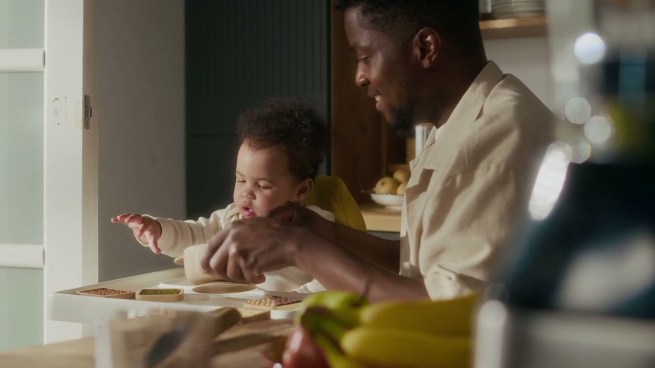 Father Feeds Baby in High Chair at Home