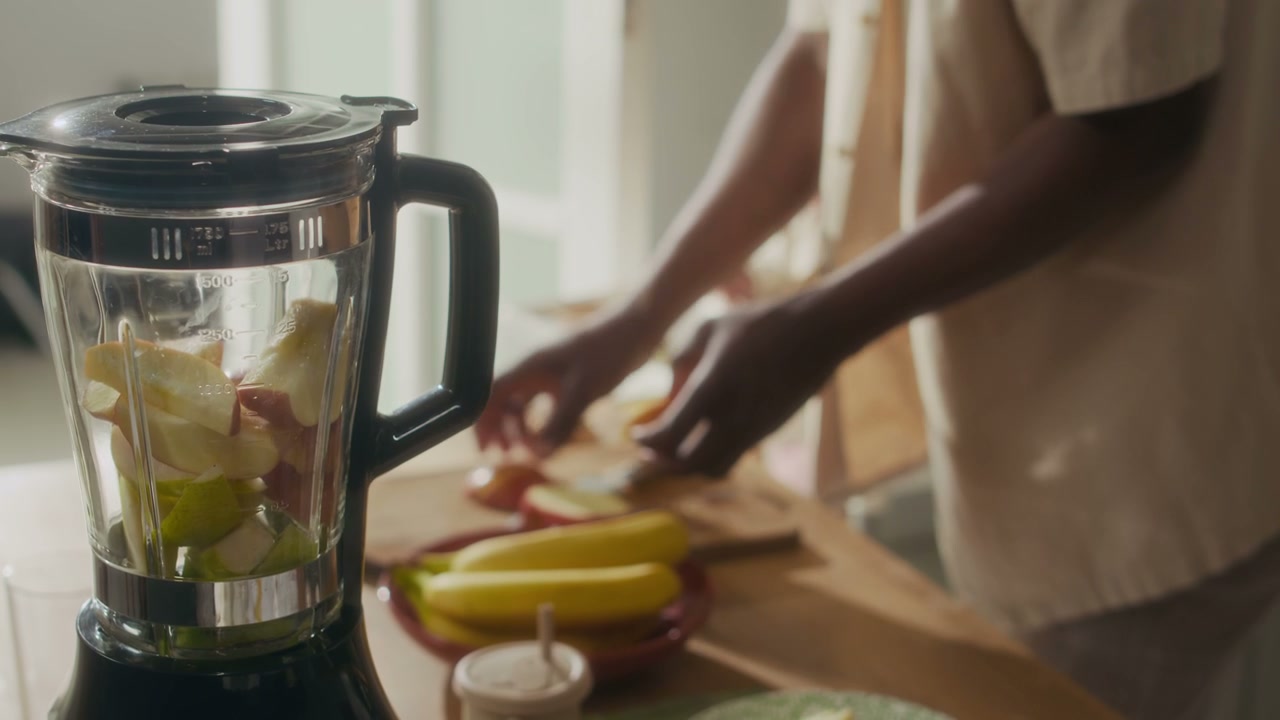 Hands Adding Fruit to Blender