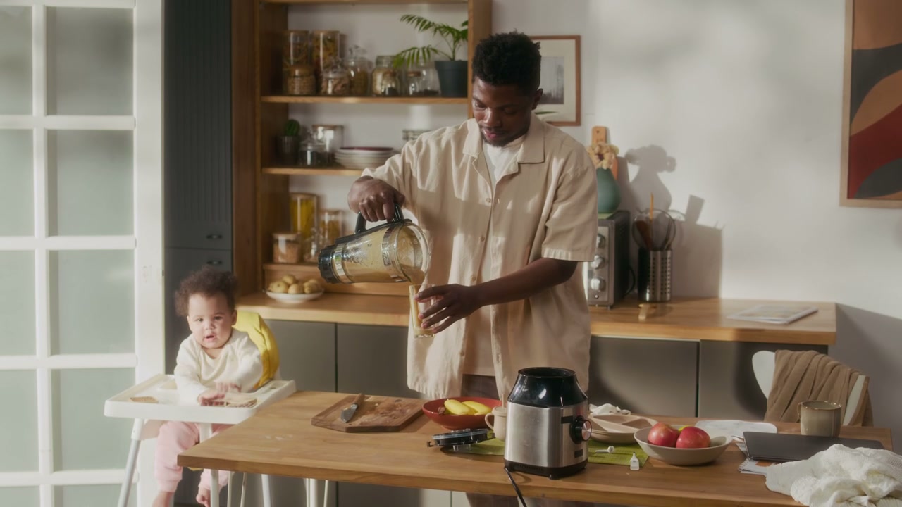 Man Pouring Smoothie in Kitchen with Baby