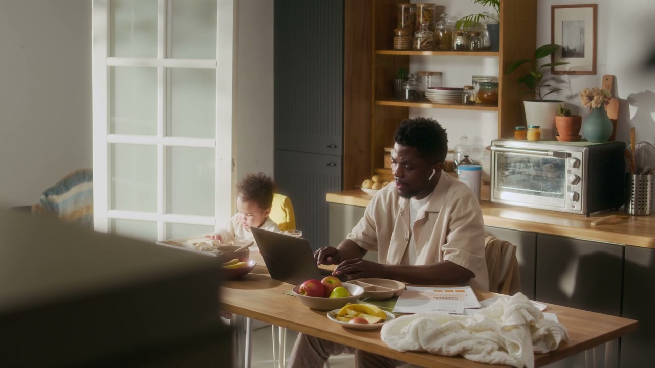Father Working Remotely with Baby in Kitchen