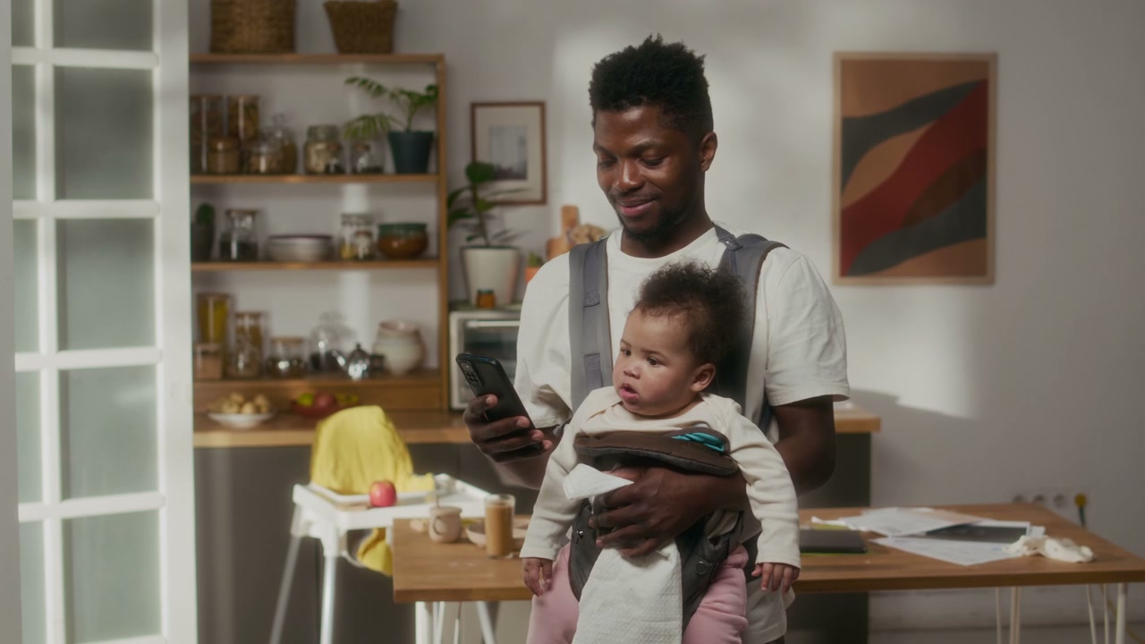 Smiling Father with Baby Using Smartphone