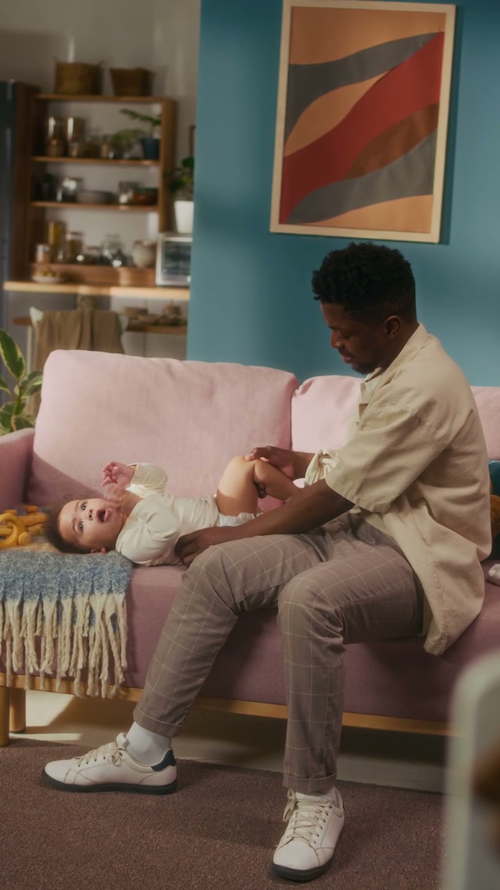 Dad Changing Baby's Diaper on Sofa