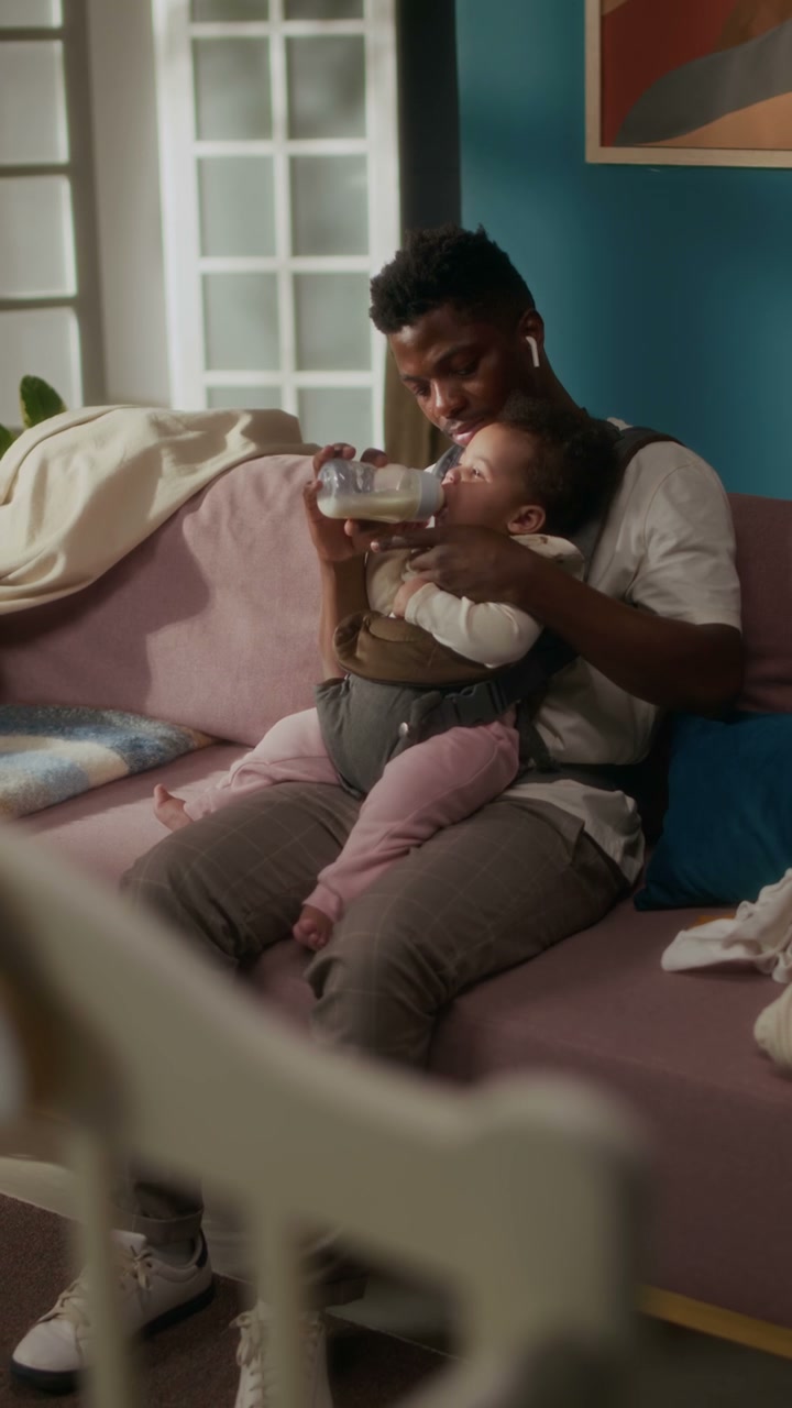 Father Feeding Baby with Bottle at Home