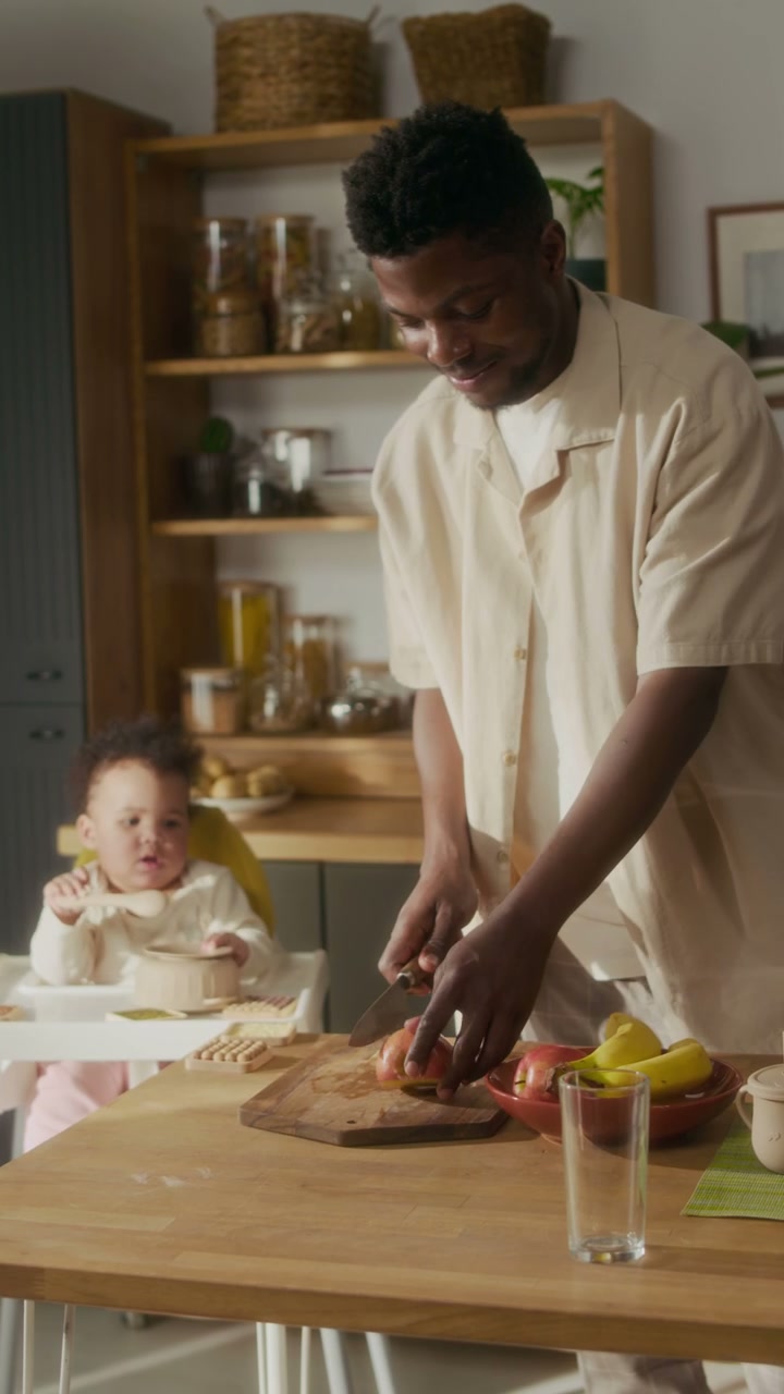 Father Cutting Fruit in Kitchen with Baby