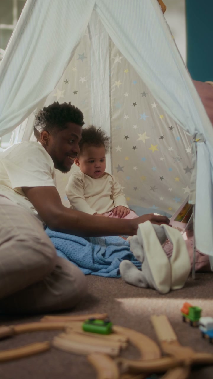 Father Reading Book to Baby in Play Tent