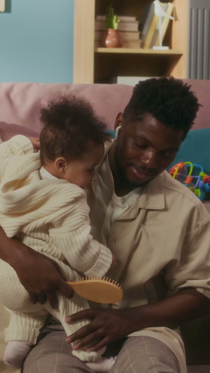 Father Brushing Baby's Hair At Home