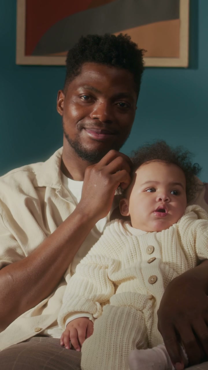 Smiling Dad Cuddling Baby on Couch