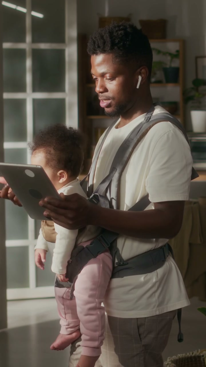 Father on Video Call with Baby in Carrier at Home