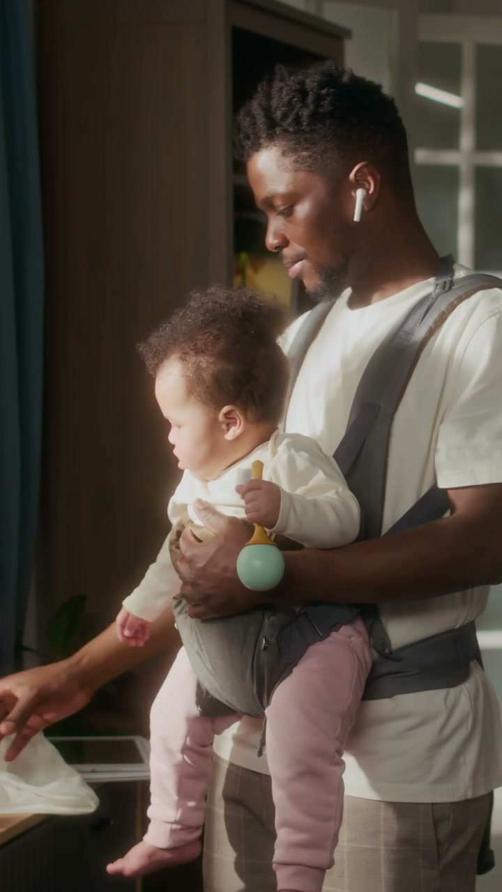 Father Preparing Baby Bottle While Wearing Child