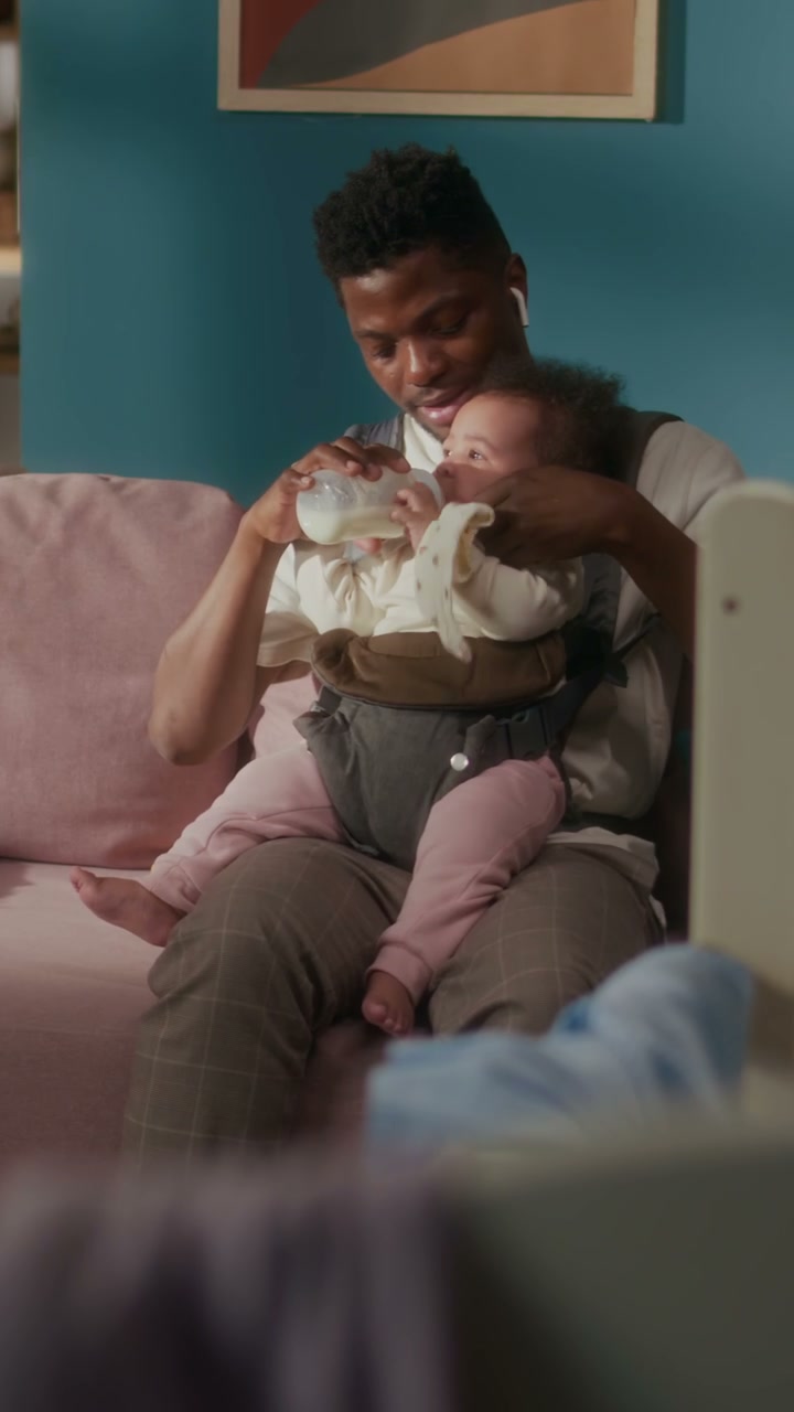 Dad Bottle-Feeding Baby on Sofa at Home