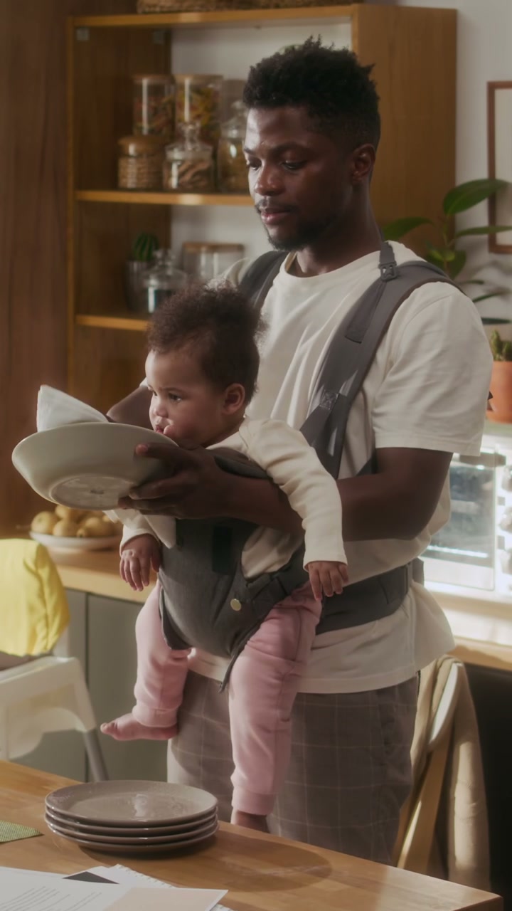 Father Wiping Dishes While Carrying Baby