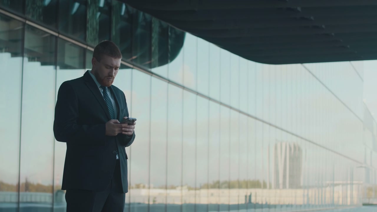 Young Businessman Using Smartphone by Skyscraper