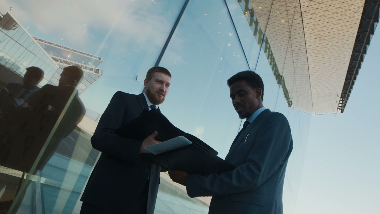 Two Businessmen Discussing Documents Outdoors