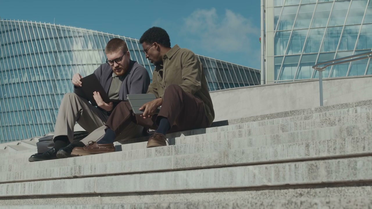 Two Men Discussing on City Stairs with Tablet