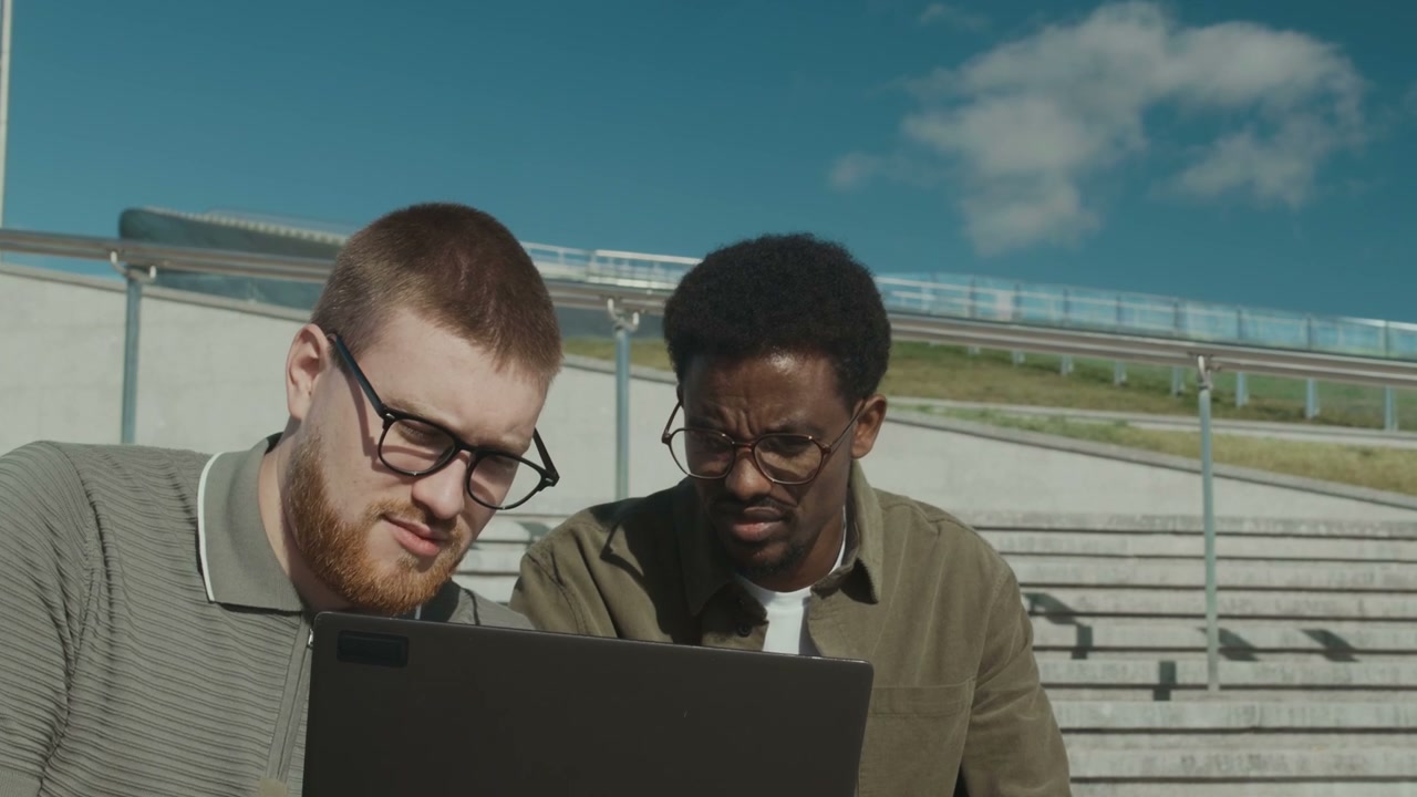 Two Men Discussing Business on Laptop Outdoors
