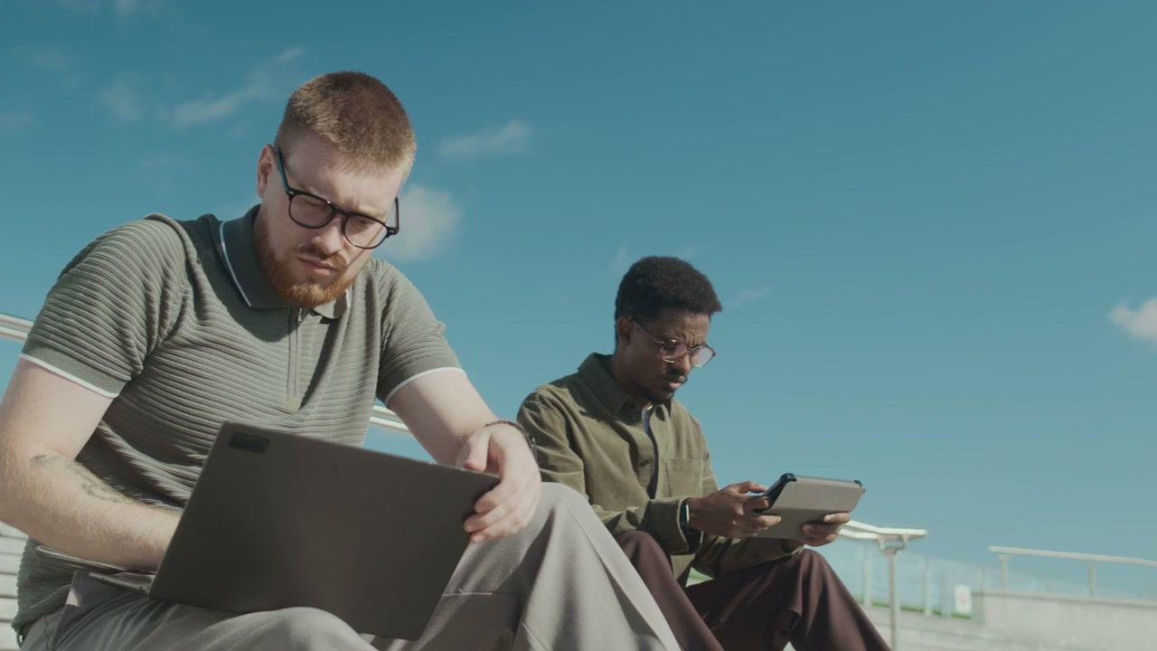 Two Men Working on Laptop and Tablet Outdoors