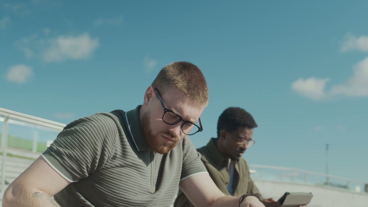 Two Men Working Outdoors on Digital Devices