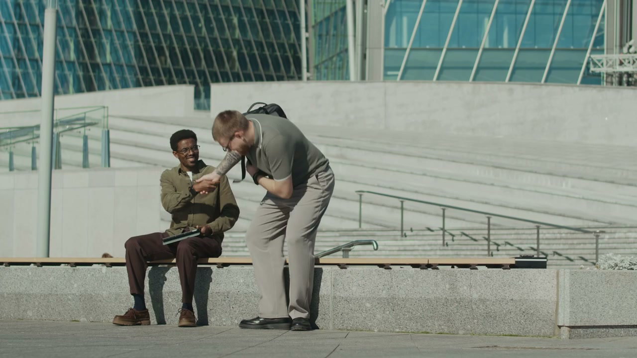 Two Men Greet and Sit on City Bench