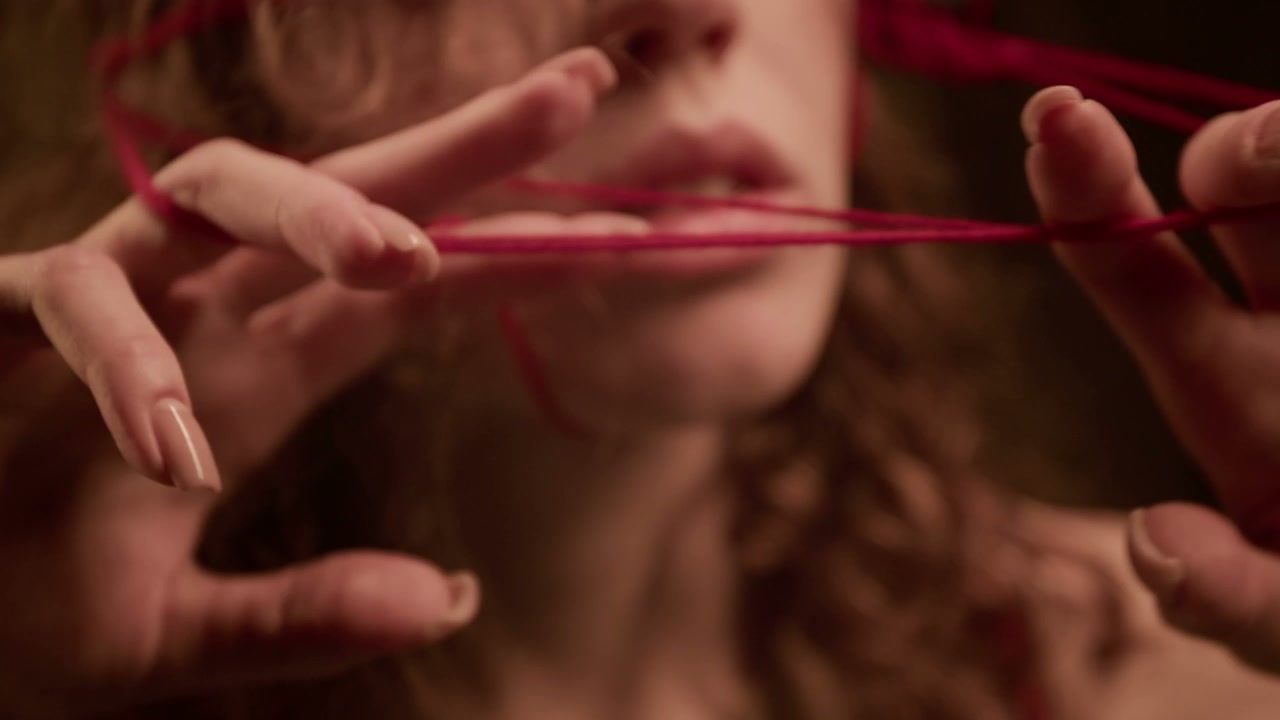 Person's Hands Tangled with Red Thread