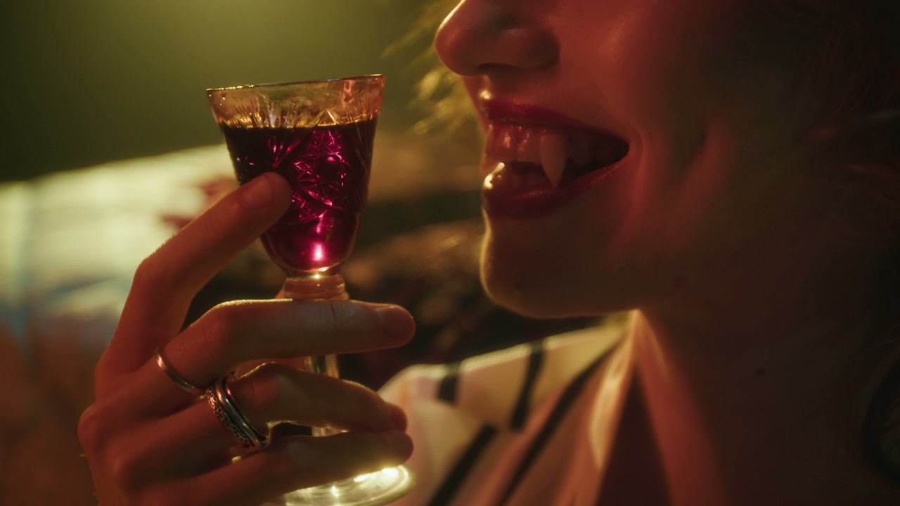 Vampire Woman Reveals Fangs and Licks Lips