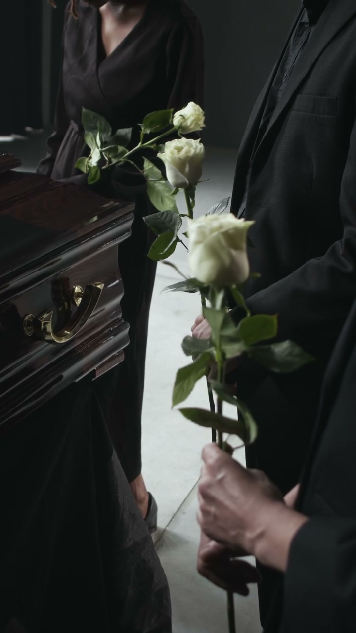 Mourners Holding White Roses at Funeral Service